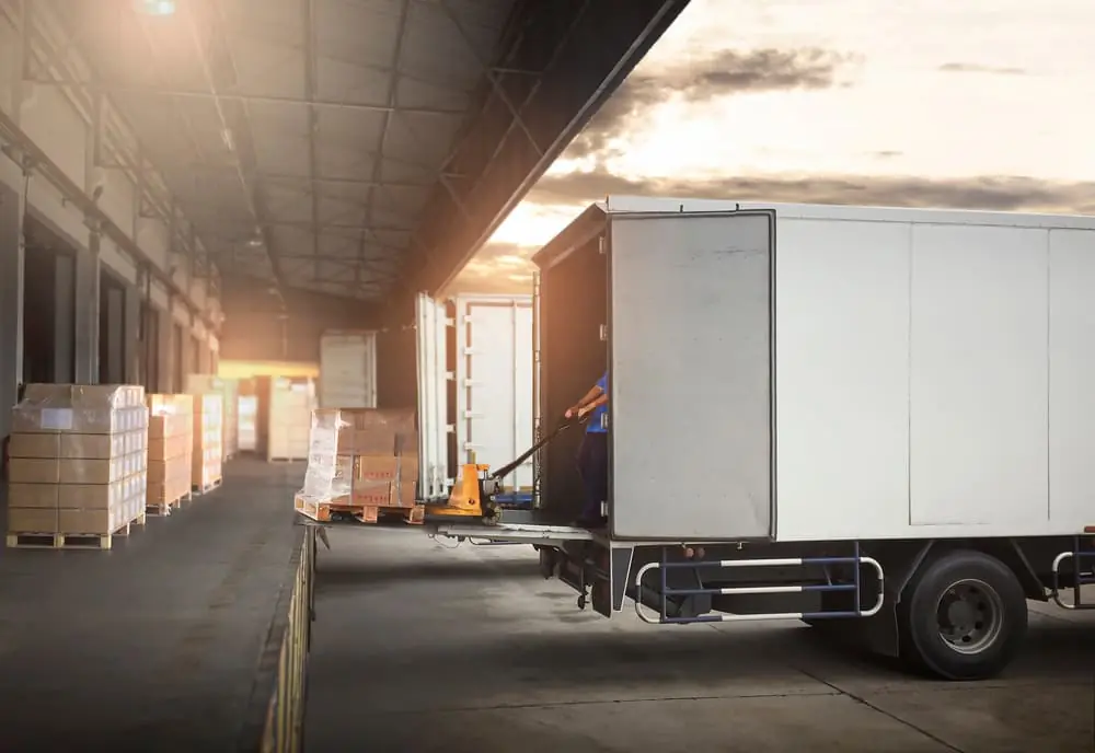 Harsh Reality of the Modern Freight Recession loading dock worker pulling a a pallet on a pallet jack into trailer