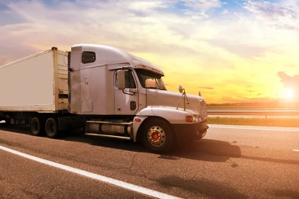 Harsh Reality of the Modern Freight Recession silver semi trailer truck driving down highway at dawn