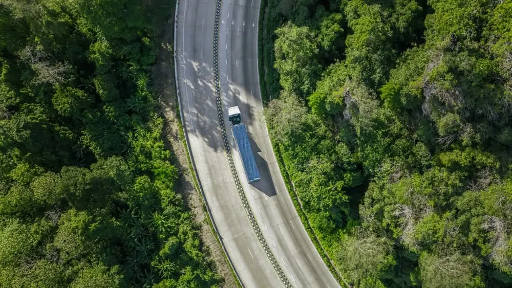 What Would Logistics Look Like If Fuel Ran Out aerial shot of a white semi trailer driving down a rural forested road