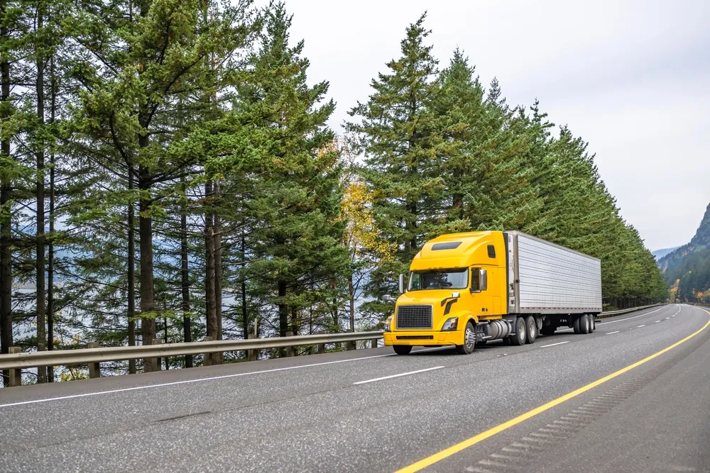 Yellow Corp Bankruptcy yellow semi trailer truck driving down forested highway