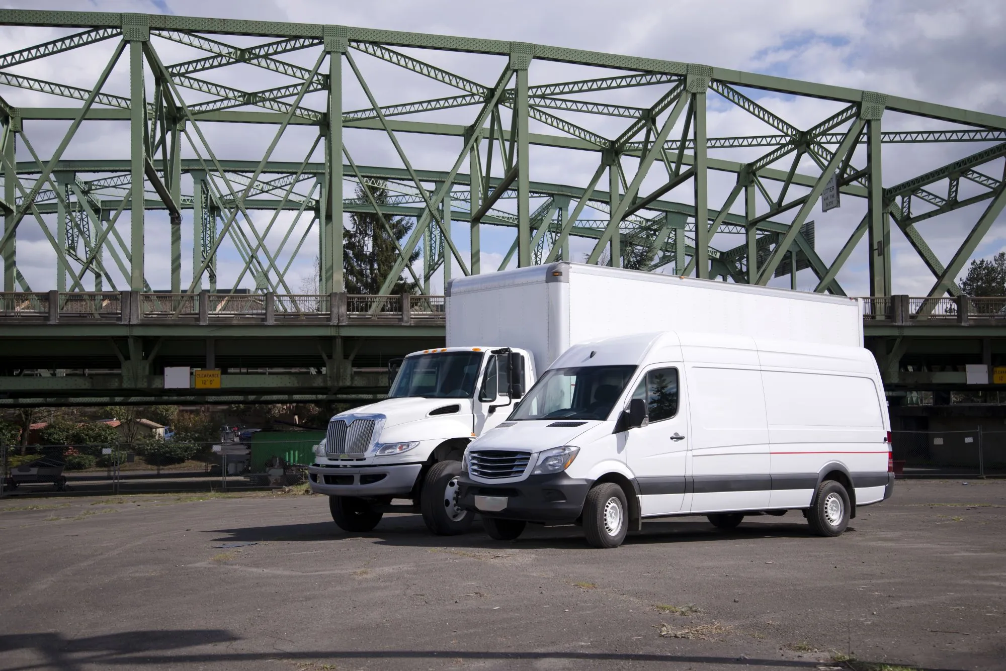 small truckload shipping options showing a cargo van next to box truck in lot by bridge