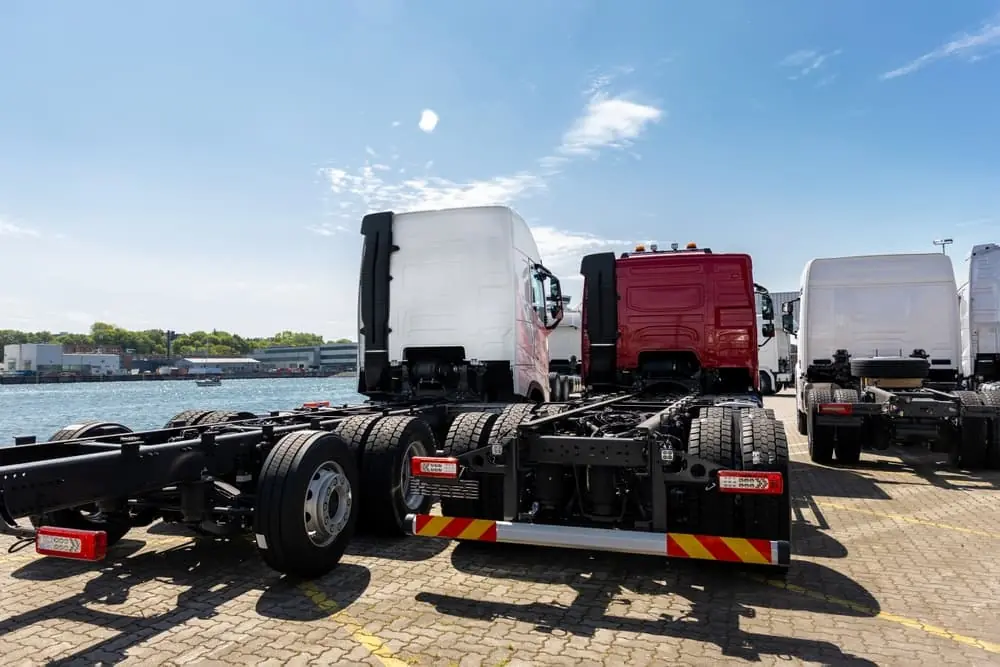 Freight Equipment Squeeze semi trailers with empty flatbeds parked next to riverbed