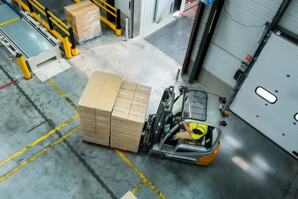 Logistics Talent Shortage topdown view of worker operating a forklift carrying a pallet through warehouse