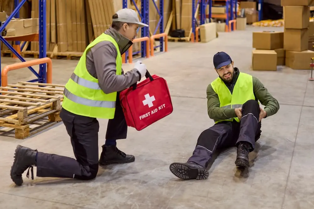 Logistics Talent Shortage warehouse worker treating injured coworker with first aid kit
