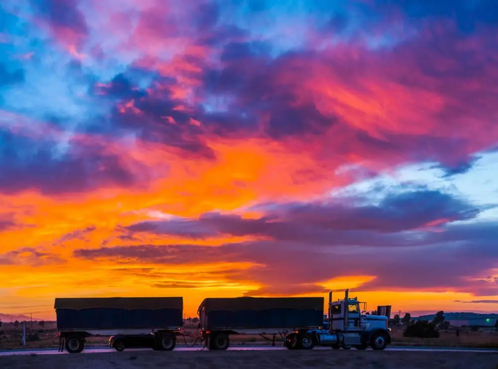 SKU-Level Risk Forecasting double trailer truck driving down desert highway at dusk