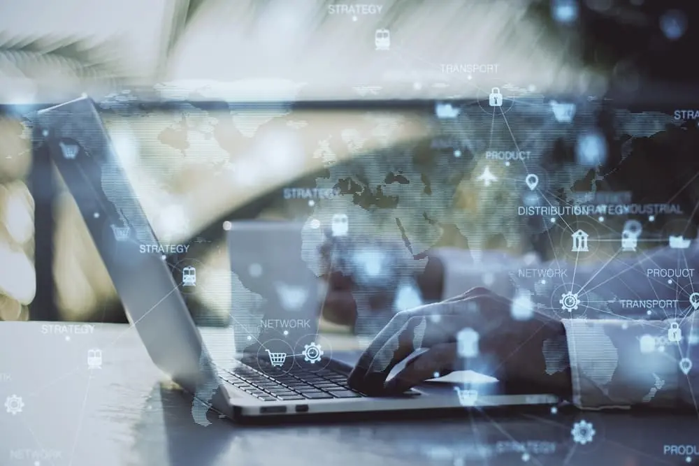 SKU-Level Risk Forecasting global map representing global trade overlaying an image of a businessperson typing on a laptop