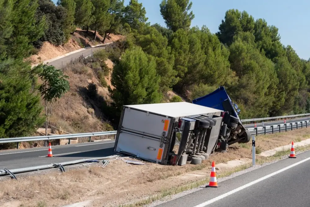 Truck Bottlenecks semi trailer truck overturned on rural desert highway with safety cones surrounding it