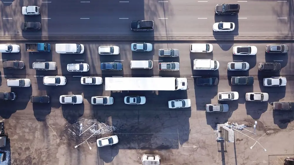 Truck Bottlenecks white semi trailer truck surrounded by white sedans during traffic jam